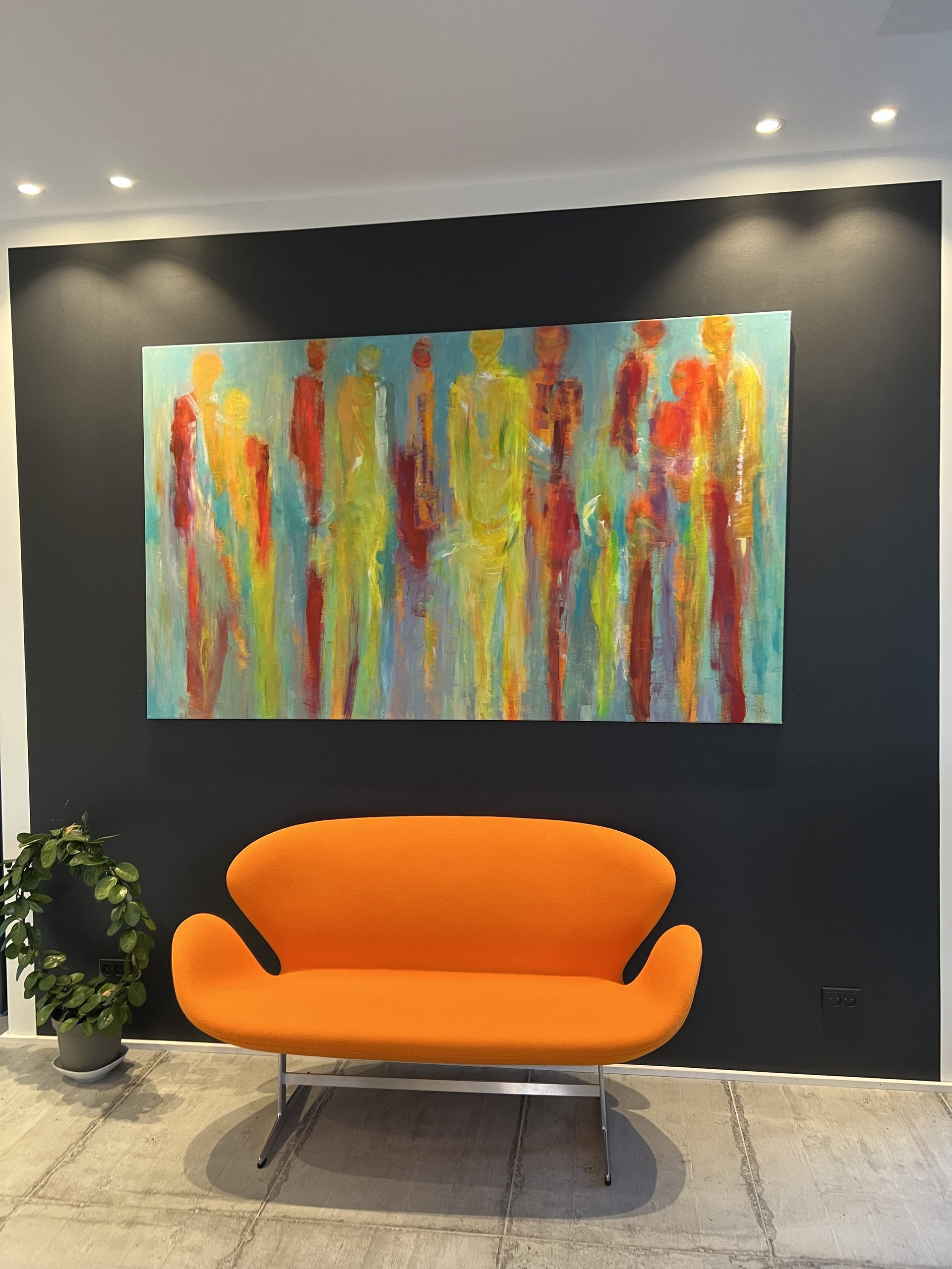 Få kunst og farver på væggen med galleri Weppler. Her stort aflangt maleri på farver væg med orange sofa placeret i stuen.